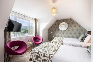 皮特洛赫里Scotland's Spa Hotel的一间卧室配有两张床和两张紫色椅子