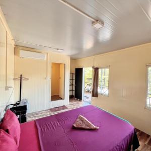 Phumĭ Chroŭy SvayCornerStone Nesat in Nesat Village的一间卧室配有一张带紫色毯子的床