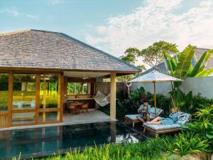 乌布Kaamala Resort Ubud by Ini Vie Hospitality的两个人坐在别墅的庭院里