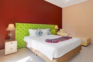 库塔The Kanjeng Hotel Kuta的一间卧室配有一张大床和绿色床头板