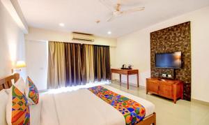 JojeraFabHotel Prime Indeedcare Hotel & Resorts的一间卧室配有一张床、一台电视和一张书桌