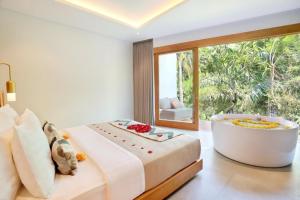 乌布Kaamala Resort Ubud by Ini Vie Hospitality的一间带浴缸和大窗户的卧室