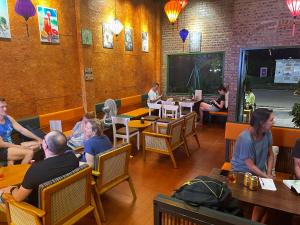 Kỳ VĩAn Hostel & Coffee Bar的一群坐在餐厅桌子上的人