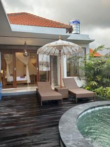 乌布Gyanesh Villa的一个带椅子和遮阳伞的庭院和一个游泳池