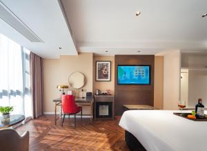 张家界Zhangjiajie Metropolo Hotel的酒店客房配有一张床、一张书桌和一台电视。