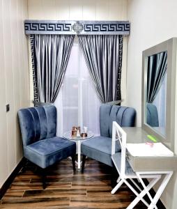 拉合尔Hotel Grand Pakeeza的一间设有蓝色椅子、一张桌子和窗户的房间