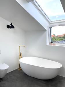 哥本哈根House in beautiful Copenhagen的一间带大型白色浴缸和窗户的浴室