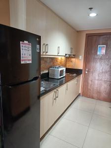 马尼拉酾尔公寓的厨房配有黑色冰箱和微波炉。