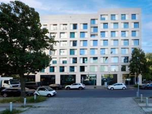 柏林柏林 - 蒂尔加滕酒店的一座白色的建筑,前面有汽车停放