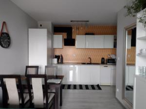 克拉科夫Apartamenty Piastów的厨房配有白色橱柜和桌椅