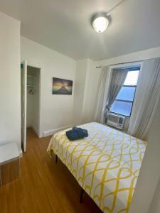 西纽约Room in a 2 Bedrooms apt. 10 minutes to Time Square!的一间卧室配有一张黄色和白色毯子的床