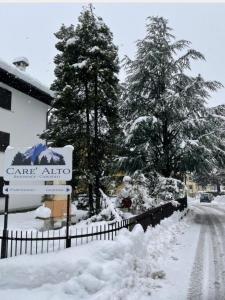 卡里索洛Carè Alto的一条有雪覆盖的街道,有树木和栅栏