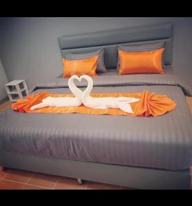 坤敬เสาวลักษณ์ เรสซิเด้นท์的两个天鹅躺在床上,床上用橙色毯子