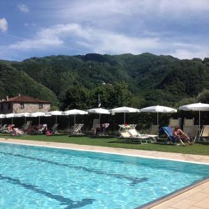 博尔戈阿莫扎诺Casa Fucina in Corsagna, Borgo a Mozzano, Lucca的山边带椅子和遮阳伞的游泳池