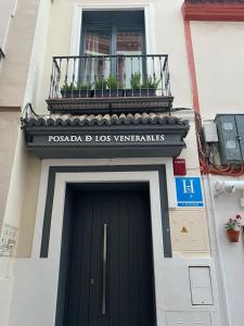 塞维利亚Posada de los Venerables的一座带黑色门和阳台的建筑