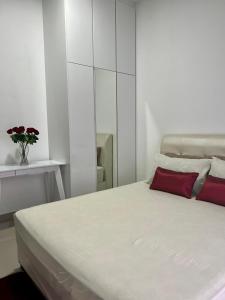 芙蓉Al Mansor Islamic Guestroom的白色卧室配有一张带红色枕头的床