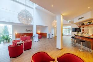 施泰尔施蒂里亚公园酒店的一间设有红色椅子的餐厅和一间酒吧