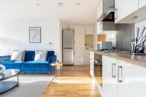 伦敦The Wembley Collection的厨房以及带蓝色沙发的起居室。