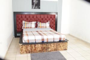 雅温得KRISTAL HOME的一间卧室配有一张带红色床头板和枕头的床。