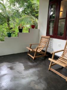 锡吉里亚Manju Homestay的两把椅子坐在房子的门廊上