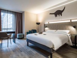 比勒费尔德ibis Styles Bielefeld City的酒店客房设有一张大床和一张书桌。