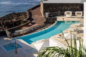 卡列罗港Royal Marina Suites Boutique Hotel的一个带椅子的游泳池,背景是大海