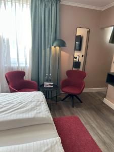 慕尼黑Hotel Metropol by Maier Privathotels的酒店客房带两把红色椅子和镜子
