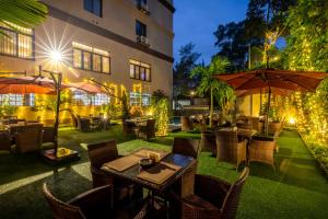 坎帕拉Best Western Plus The Athena Hotel Kampala的室外餐厅设有桌椅和遮阳伞。