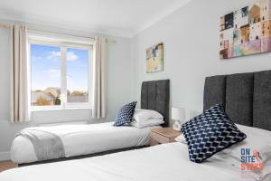 NorthfleetOnSiteStays - Cosy 2-Bedroom Apartment with Free Parking, Wi-Fi & London Links的卧室设有两张床,带窗户