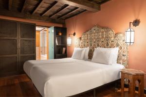 格拉纳达圣保拉宫傲途格精选酒店的卧室配有一张白色大床和床头板