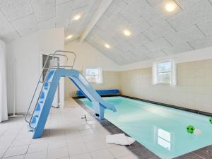 博托比24 person holiday home in Idestrup的一个带蓝色滑梯的游泳池
