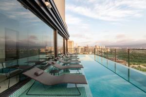 伊塔佩马Tri Hotel Premium Itapema的一座建筑物屋顶上带躺椅的游泳池