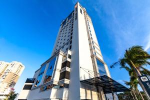 伊塔佩马Tri Hotel Premium Itapema的棕榈树高大的白色建筑