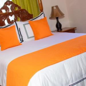 Buff BayWindbreak Villa的一张带橙色和白色床单的床和一盏灯