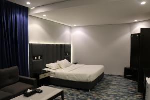 艾卜哈قمم بارك Qimam Park Hotel 1的配有一张床和一把椅子的酒店客房