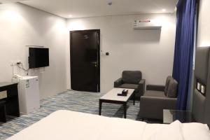 艾卜哈قمم بارك Qimam Park Hotel 1的一间带床和两把椅子的房间以及一台电视