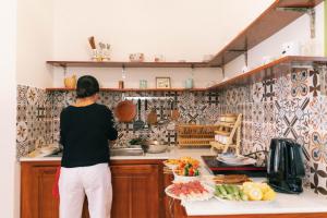 槟知Entire House - Nhà nguyên căn - Nhà Mơ Homestay Bến Tre的站在厨房准备食物的妇女