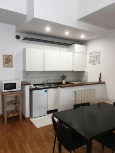 安科纳王维特立住宅酒店的厨房配有白色橱柜、黑色桌子和淡雅的桌子。