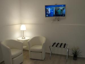 拉古萨La Voce del Violino的客厅配有两把椅子和墙上的电视