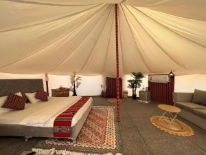 BadīyahAl Salam Desert Camp Bidiya的一间卧室配有一个带一张床和一张沙发的帐篷