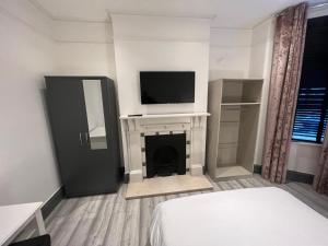 克罗伊登Rooms in Modernised Victorian House的一间卧室设有一张床,壁炉上配有电视