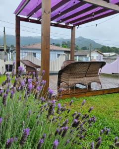 乌鲁比西Pousada Morada dos Sonhos的长凳,坐在带紫色花的甲板上,在凉棚下