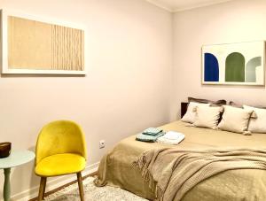 托里什韦德拉什Apartamento Torres Vedras Centro的一间卧室配有一张床和一张黄色椅子