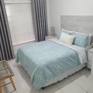 德班Overport Durban Halaal Accommodation "No Alcohol Strictly Halaal No Parties" Entire Luxury Apartment, 2 Bedroom, 4 Sleeper, Self Catering, 300m from Musjid Al Hilaal的一间卧室配有一张带蓝色床单的床和一扇窗户。