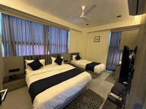 艾哈迈达巴德HOTEL ASIANA SKY Motera Ahmedabad的一间卧室配有两张床和一台平面电视