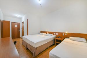里梅拉Hotel Nacional Inn Limeira的酒店客房设有两张床和一张桌子。