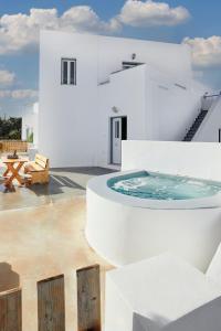 易莫洛林Athiri Santorini Hotel的白色的房子,在庭院设有热水浴缸
