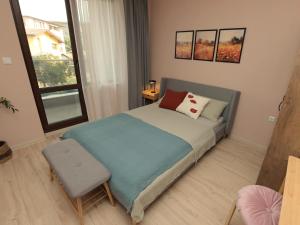 卡赞勒克Kalina Apartment Kazanlak的一间卧室配有一张带椅子的床和一扇窗户