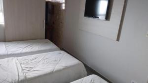 普鲁登特总统城HOTEL ITAVERÁ BRASIL的客房设有两张床和一台墙上的电视