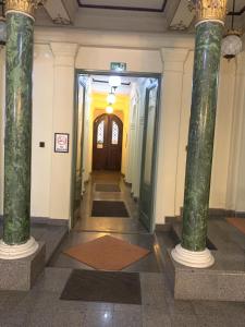 布达佩斯Kecskeméti Rooms的绿色柱子建筑的走廊